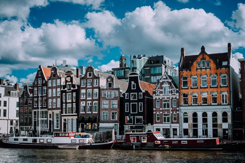 Wonderful architecture of Amsterdam. White fluffy clouds over Leaning Houses Amsterdam, Netherlands.